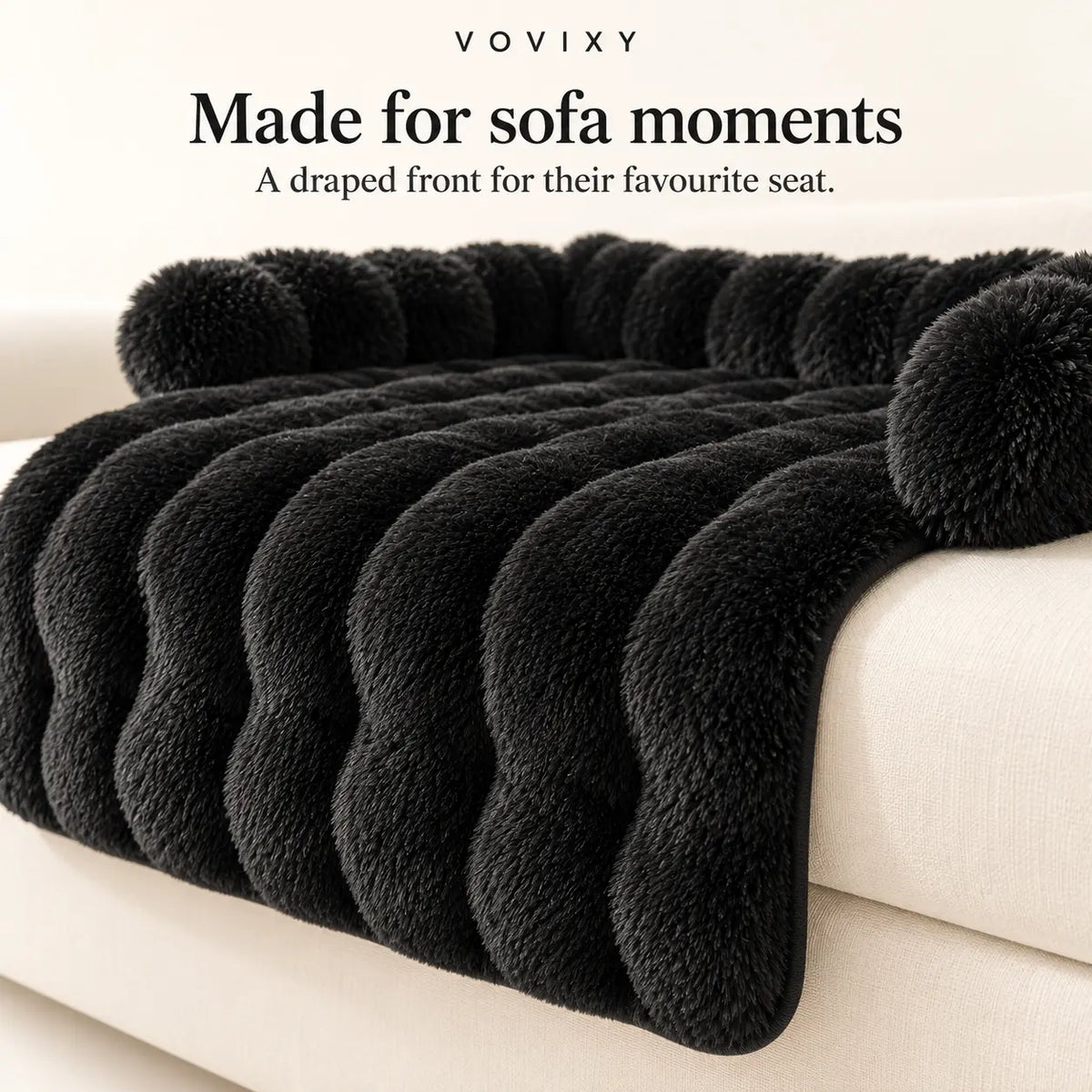 Black plush dog sofa mat showing its padded edges and front panel draped over the sofa cushion