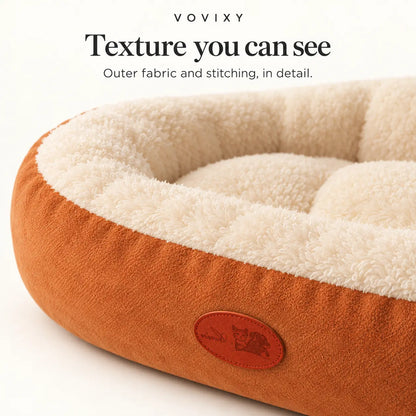 Close-up of the Caramel Brown pet bed exterior, cream plush lining and stitched front patch