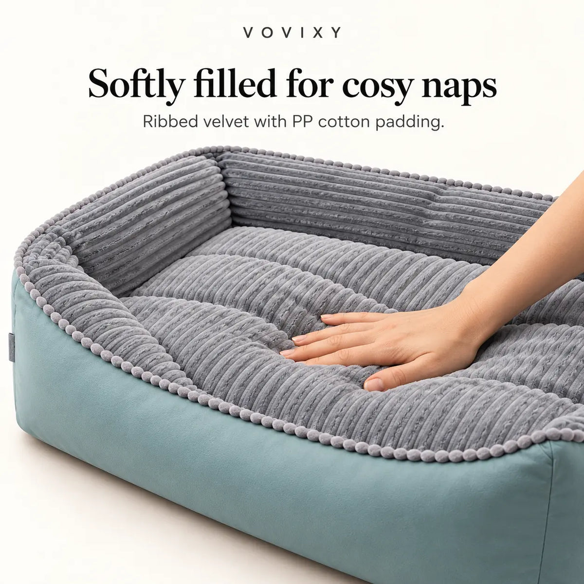Hand pressing the softly padded grey ribbed velvet sleeping area of the dog sofa bed