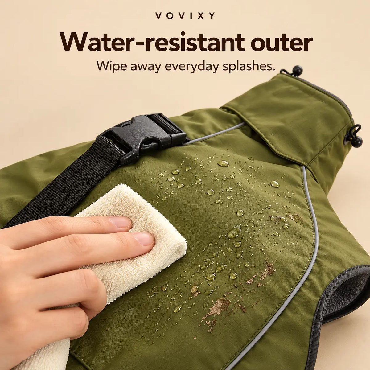 Olive Green coated dog windbreaker being wiped clean, with water droplets on the outer fabric