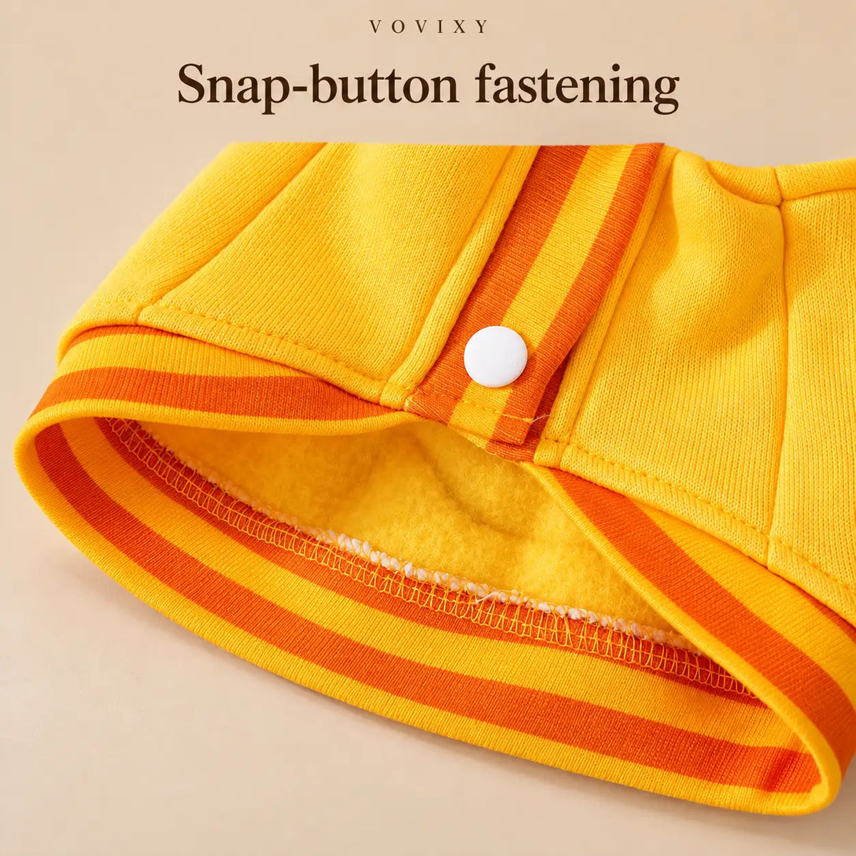 Close-up of a front snap button and orange striped hem on the Yellow Bear dog sweatshirt